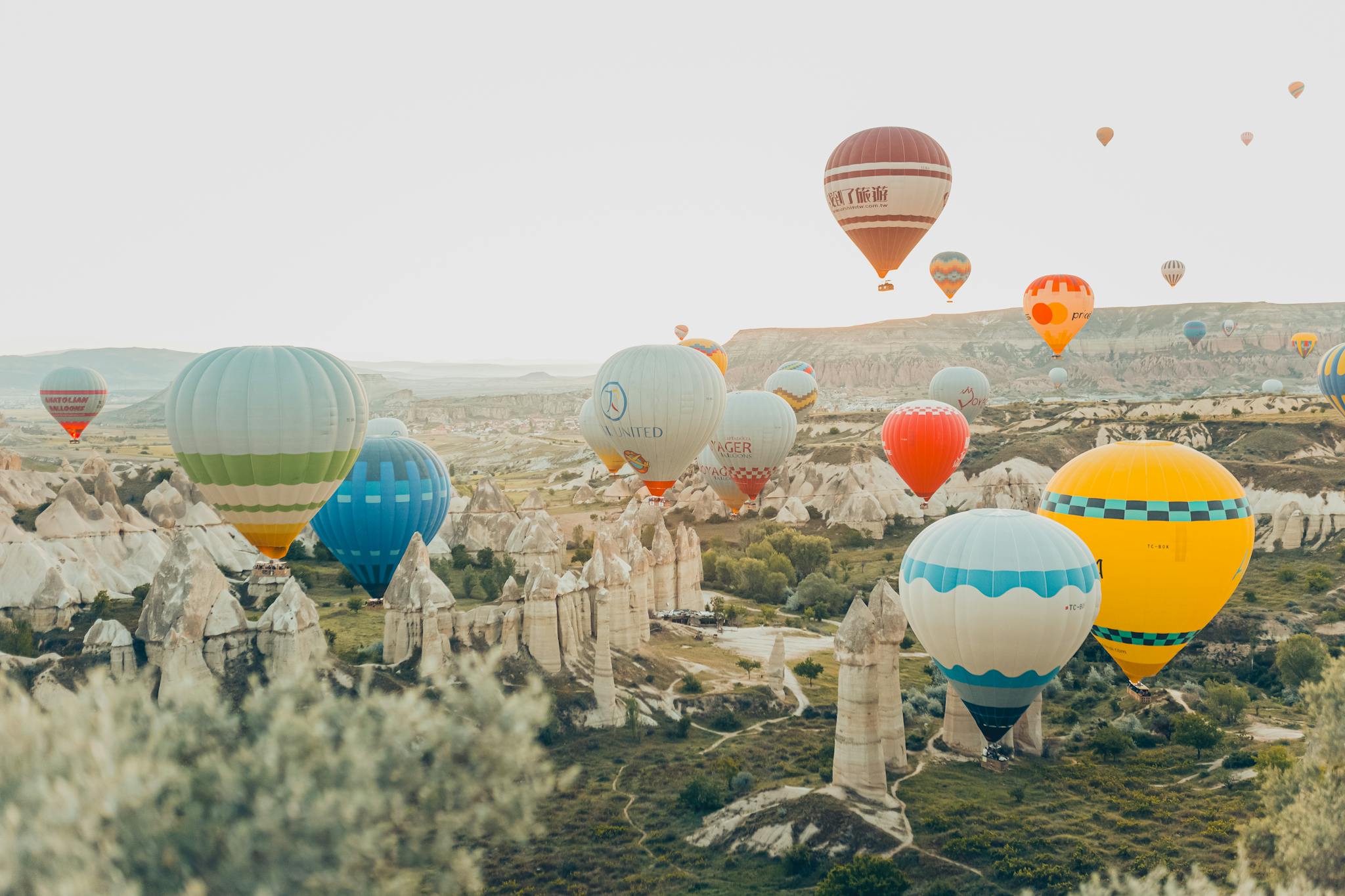 Colorful hot air balloons soar over Cappadocia's unique rock formations in Nevşehir, Türkiye.